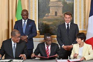 Le président du Gabon Brice Oligui Nguema et Emmanuel Macron regardent la PDG d’Eramet Christel Bories signer un accord avec le directeur général d’Ogooue Mining Leod Paul Batolo et le ministre des mines du Gabon Sosthene Nguema Nguema.